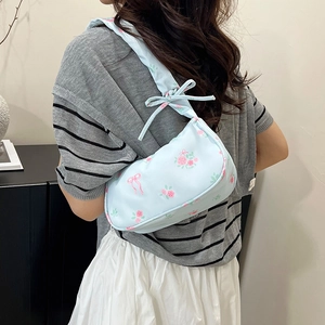 Floral shoulder bag with pink roses and bow ties on light blue fabric in lifestyle view
