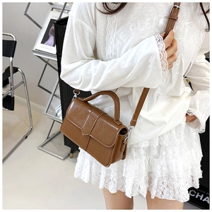 Close-up of vintage brown leather crossbody bag with top handle and silver hardware