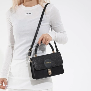 Elegante borsa nera a tracolla con patta glitterata e logo dorato indossata da modella