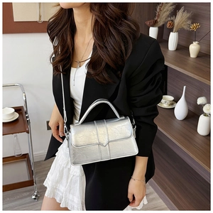 Detail of silver metallic textured crossbody bag with V-shaped buckle and strap