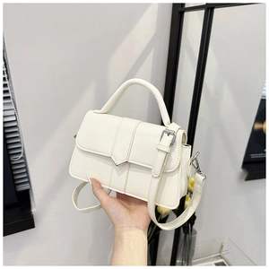 Detail view of a cream white crossbody bag with geometric flap and matching top handle