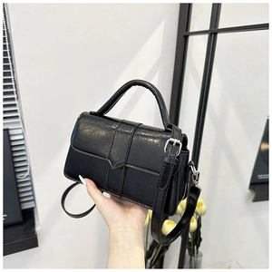 Detailed macro of black oil-wax leather texture and silver hardware on square handbag