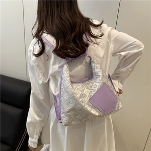 Sac fourre-tout tissé à motif géométrique et garniture en cuir violet, porté à l'épaule