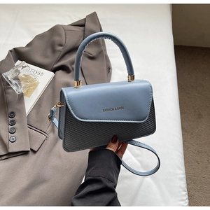 Fashionable light blue and black handbag held by model with elegant styling details
