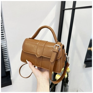 Close-up of vintage brown crossbody bag with glossy cracked leather texture and top handle