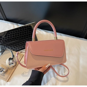 Pink crossbody bag detail showing leather texture, woven design, and gold fashion lettering