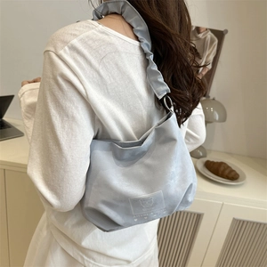 Light blue crossbody bag with ruffled strap and bear graphic in a lifestyle setting