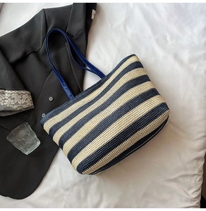Top view of a blue and white striped woven tote bag with long straps on a white fabric