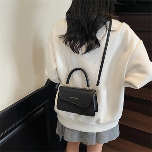 Chic black textured PU leather crossbody bag with top handle shown on a model