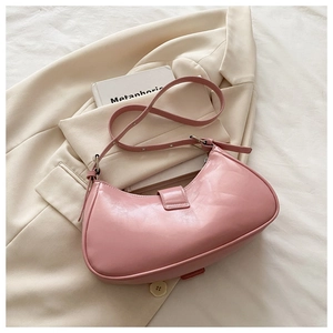 Top view of pink semi-circle shoulder bag with glossy finish on beige blazer fabric
