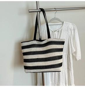 Detail of classic black and white striped woven tote bag with premium faux leather straps