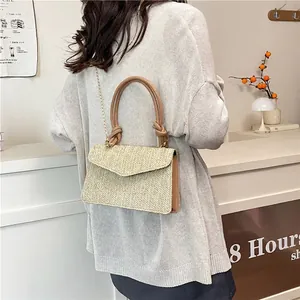 Sac à main en paille tressée avec anses en cuir marron et chaîne dorée sur mannequin