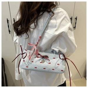 Close-up of light blue canvas bag with red bows, heart pendant and fine ribbon detail
