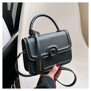 Detail of minimalist black crossbody square bag with arc handle and fashion tag