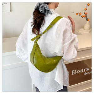 Detail of green crescent moon bag with silver eyelets on wide leather strap