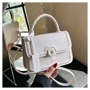 Close-up of ivory crossbody bag featuring a golden fashion tag and chic square buckle