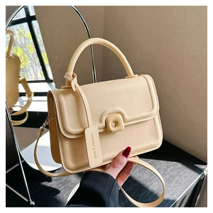 Detail view of cream crossbody bag with leather texture and square decorative buckle