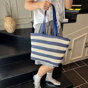 Blue and white striped woven tote bag with leather handles for summer travel