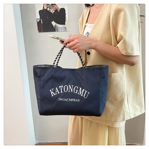 Close-up of navy blue tote bag with white lettering and sporty woven rope handles
