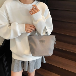 Minimalist grey casual handbag with Fashion label shown by a model on stairs