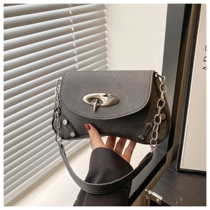 Detail of black leather shoulder bag featuring an irregular silver buckle and metal rivets