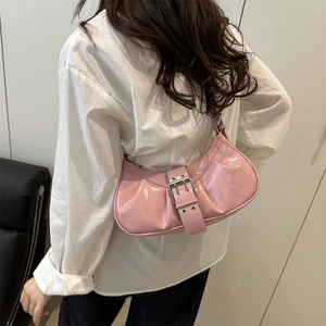 Pink patent leather underarm bag with metal buckle shown on model in modern setting