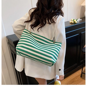 Detailed view of green and white striped canvas tote bag with elegant gold chain strap