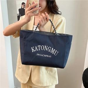 Dark blue nylon tote bag with striped handles held by model for casual commuting