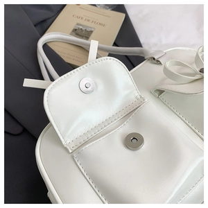 Close-up of white PU leather bag flap featuring a silver magnetic snap button closure