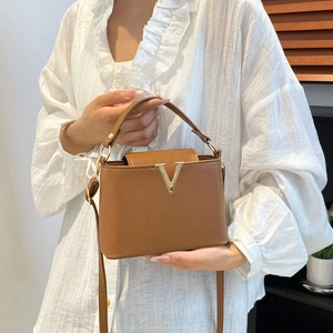 Caramel brown leather handbag with gold V-buckle and adjustable strap for women
