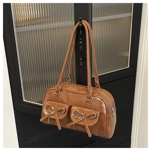 Close-up of vintage brown PU leather Boston bag with decorative bows and silver hardware