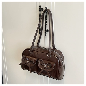 Detail of dark brown PU shoulder bag featuring dual front pockets and bow accents