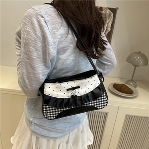 Sac bandoulière chic noir et blanc avec nœud, imprimé cœur et motif vichy sur un modèle