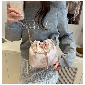 Detail of pink jacquard bucket bag with pearl handle and silk embroidery texture
