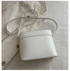 Detailed top view of white leather bucket bag with silver metal buckles and adjustable strap