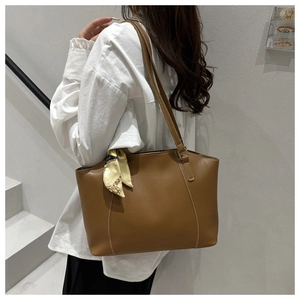 Sac fourre-tout en similicuir marron avec surpiqûres et foulard en soie porté par un mannequin