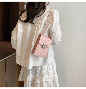 Sac à téléphone rose matelassé avec boucle nœud en métal porté sur l'épaule