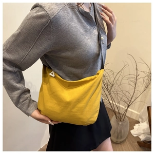 Detail of bright yellow nylon dumpling crossbody bag featuring a soft curved structure