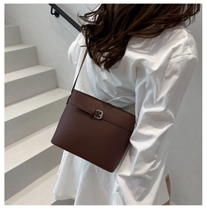 Detailed view of chocolate leather bucket bag with silver metal buckle and embossed logo