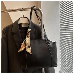 Détail d'un cabas en cuir noir avec surpiqûres contrastées et foulard décoratif en soie