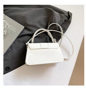 Detail of white leather handbag showing wide top handle and metal lock closure