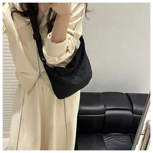 Adjustable wide fabric strap on a black nylon crescent bag shown on a casual model outfit