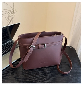 Top view of coffee brown leather bucket bag on desk with embossed logo detail
