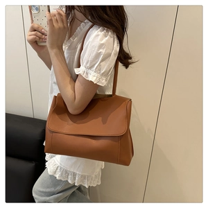 Side view of a vintage brown leather tote bag with flap closure on female model