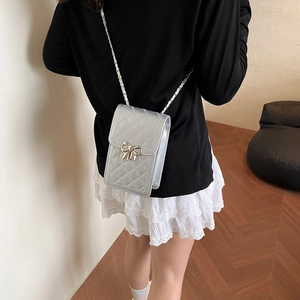 Mini sac bandoulière argenté matelassé avec fermoir nœud métallique porté par mannequin