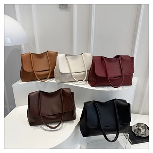 Selection of five large leather tote bags in various colors on a minimalist display stand