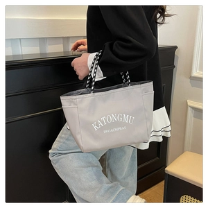Detail of grey nylon tote bag with striped woven handles and side pocket storage