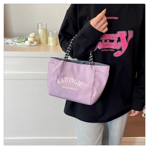 Detail of lavender nylon tote bag featuring woven handles and side pockets in a lifestyle setting