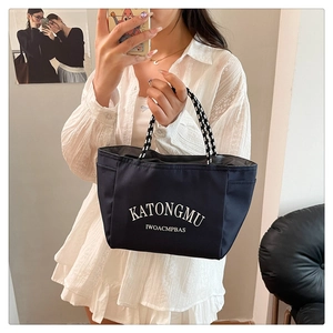Detail of dark blue nylon tote with striped rope handles and white letter print