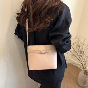 Minimalist beige leather bucket bag with silver buckle and crossbody strap for women
